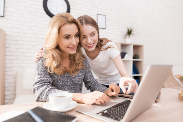 mother-daughter-watching-into-laptop-home_85574-2277